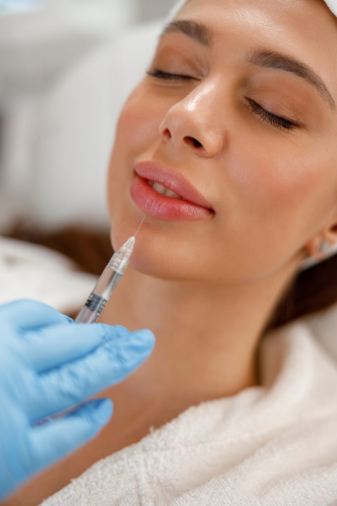 Closeup of young woman getting rejuvenating injections in lips at beauty salon