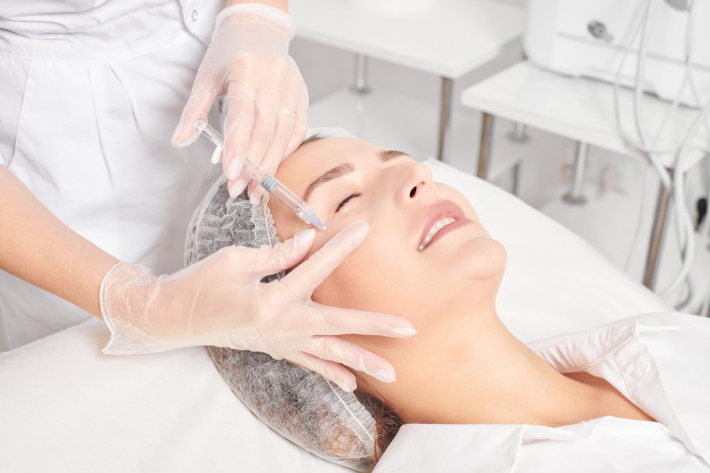 Cosmetologist makes rejuvenation injection in woman face, anti aging procedure in beauty salon