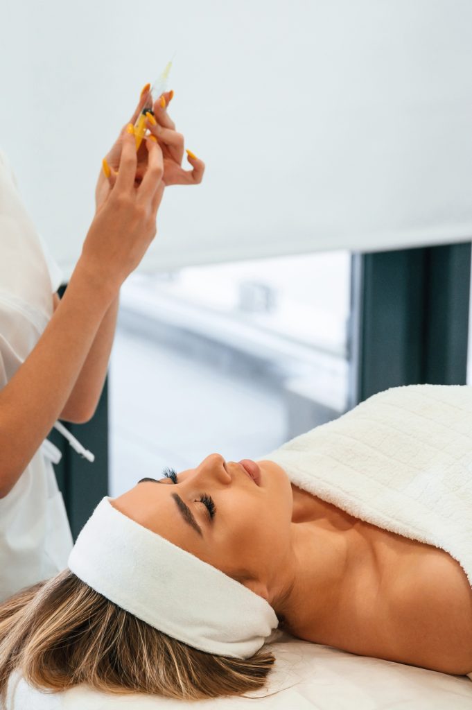 Getting ready for injection. Woman face getting facial care by beautician hands at spa salon