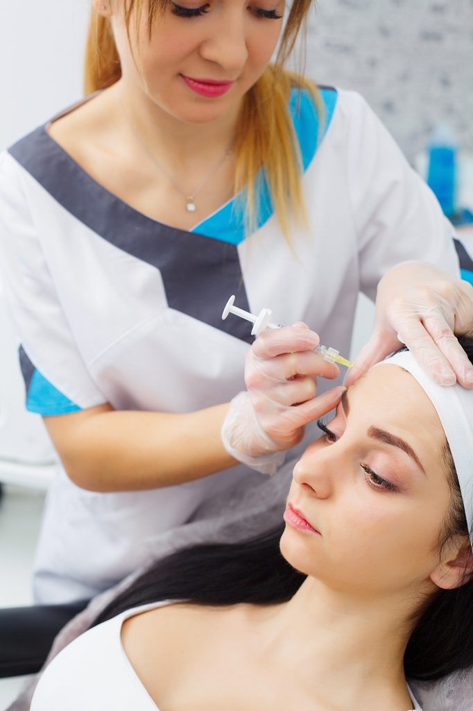 Young woman gets beauty facial injections in the cosmetology salon. F