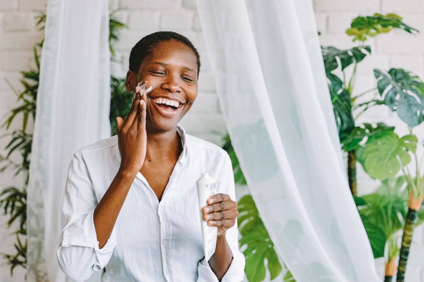 Mujer aplicándose crema con fotoprotección en la mejilla